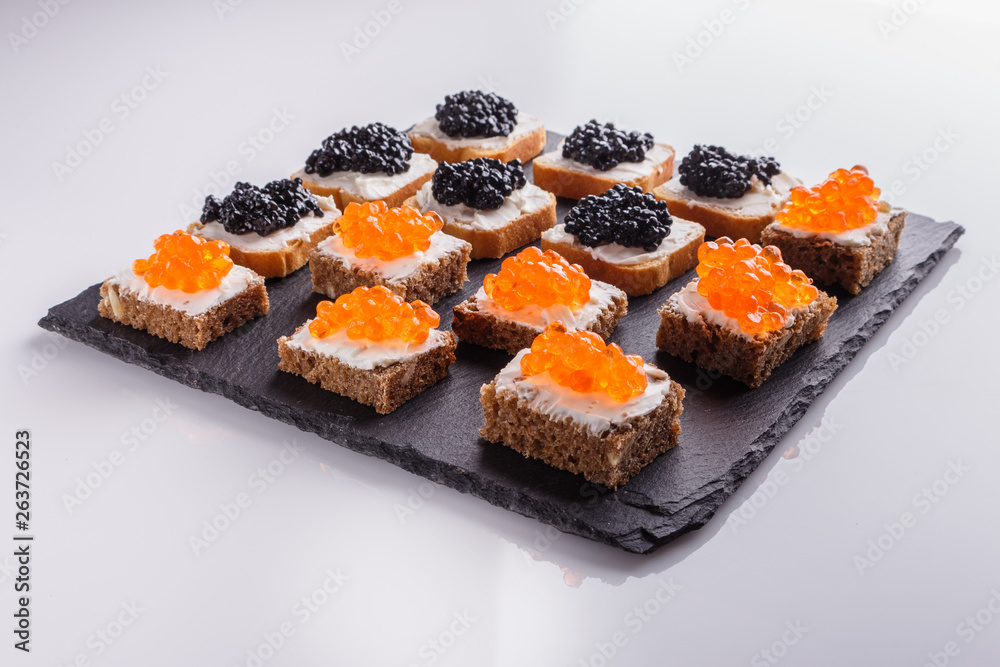 Snack with red and black caviar on a stone plate