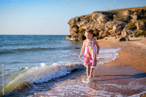 Teen girl in summer dress jumping on the beach at the day time