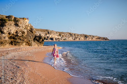 Happy child running and jumping in the waves during summer vacation on exotic tropical beach. Holiday on ocean coast for family with young children. Kids play at the sea