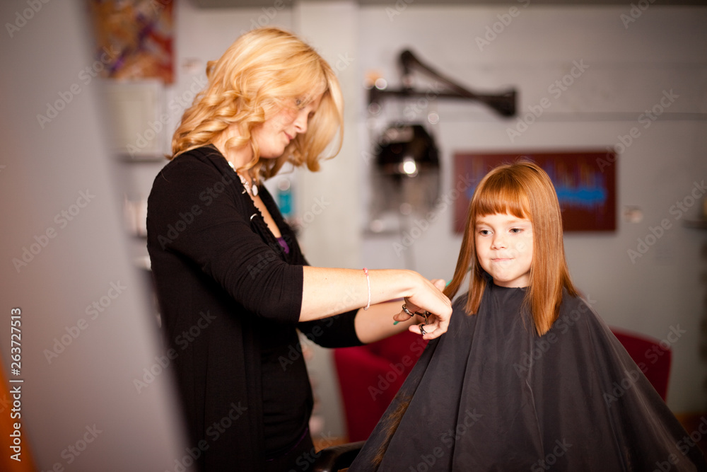 Fototapeta premium Red-Haired Girl Getting Haircut in Hair Salon