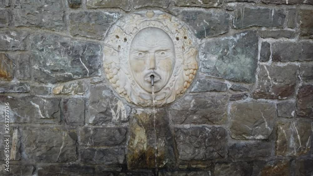 Selvino, Bergamo, Italy. Water spurting from the fountain with a marble mask in the center of the village. Selvino is a mountain resort Selvino, Bergamo, Italy. Water spurting from the fountain with a marble mask in the center of the village. Selvino is a mountain resort