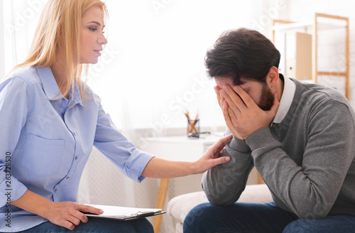 Depressed man crying at psychotherapy in despair
