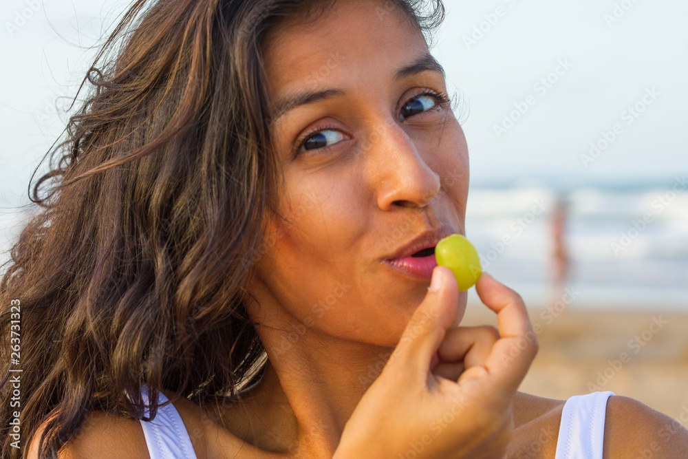 Young indian woman eating fruit on the beach Young indian woman eating fruit on the beach
