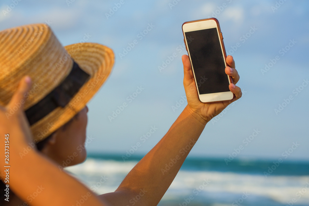 young indian woman taking photo on the beach
