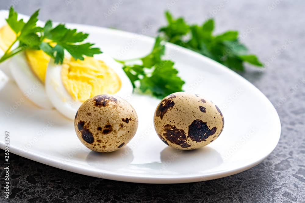 Boiled chicken eggs with quail eggs and parsley on the white plate Boiled chicken eggs with quail eggs and parsley on the white plate