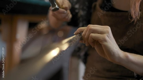 A female silversmith hammers a silver ring into shape photo