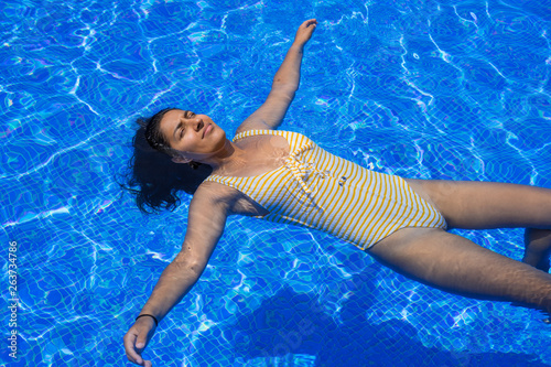 Young indian woman floating in the pool