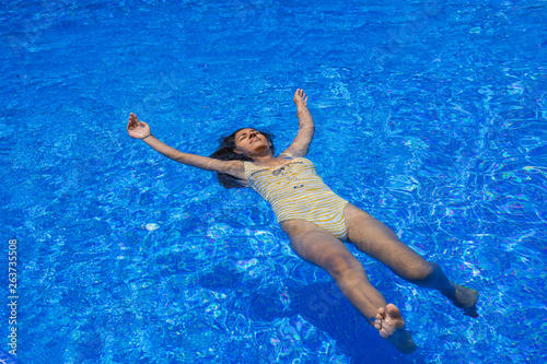 young indian woman floating in the pool