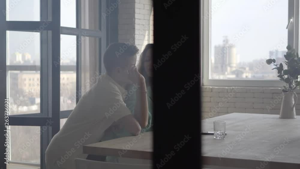 The son embraces a tired mother standing at the table indoors. Brotherhood. Family relationship. The son embraces a tired mother standing at the table indoors. Brotherhood. Family relationship.