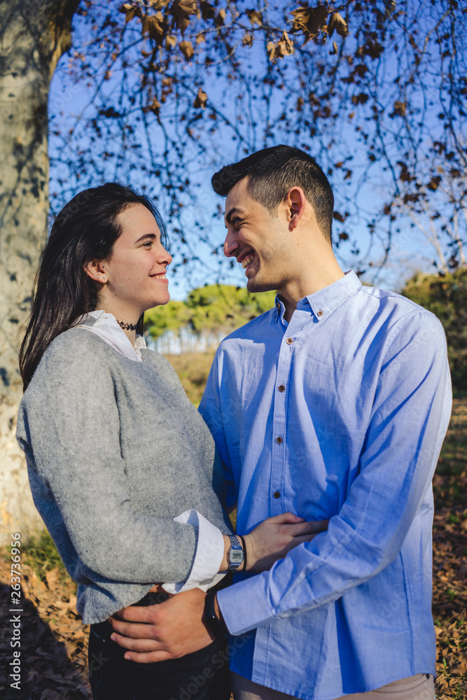 Fototapeta premium Happy young couple smiling and hugging in a forest in the middle of nature on a sunny spring day.