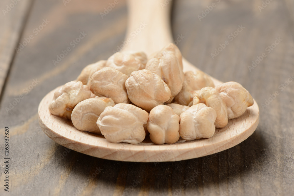 Garbanzos gordos en una cuchara de madera sobre fondo de madera, detalle Garbanzos gordos en una cuchara de madera sobre fondo de madera, detalle