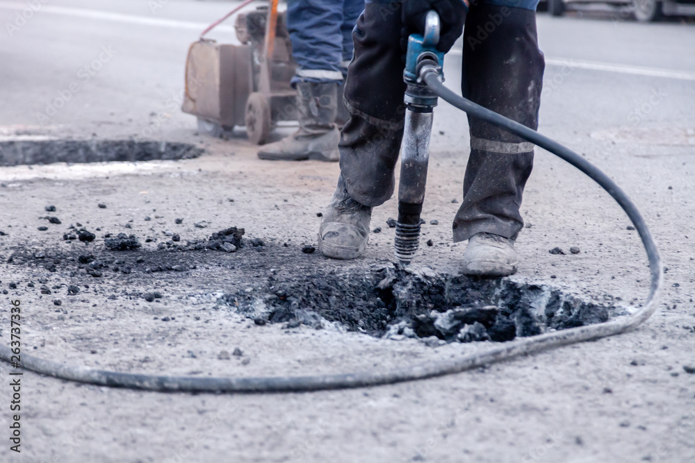Φωτογραφία Closeup of a photo of professional workers in uniform repairing asphalt road with a jackhammer