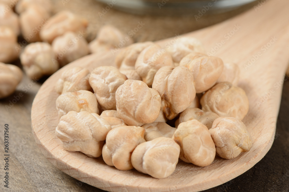 Garbanzos gordos en una cuchara de madera sobre fondo de madera, detalle Garbanzos gordos en una cuchara de madera sobre fondo de madera, detalle