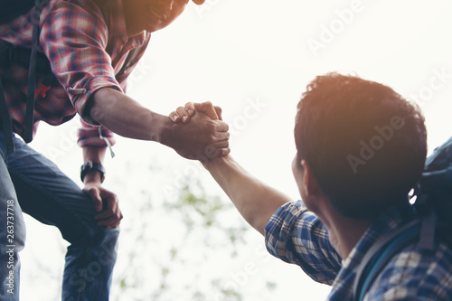 Foto Two travelers are pulling their hands together to help their friends up