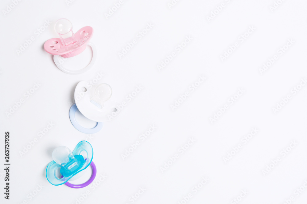 Three colorful baby silicone pacifier with holder on white background. Mock up. Flat lay. Orthodontic dummy for baby