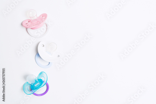 Three colorful baby silicone pacifier with holder on white background. Mock up. Flat lay. Orthodontic dummy for baby © karlevana