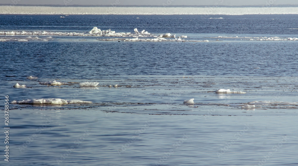 Snow pile, hill. Large snow drift isolated on a blue sky background,  outdoor view of ice blocks at frozen finland lake in winter