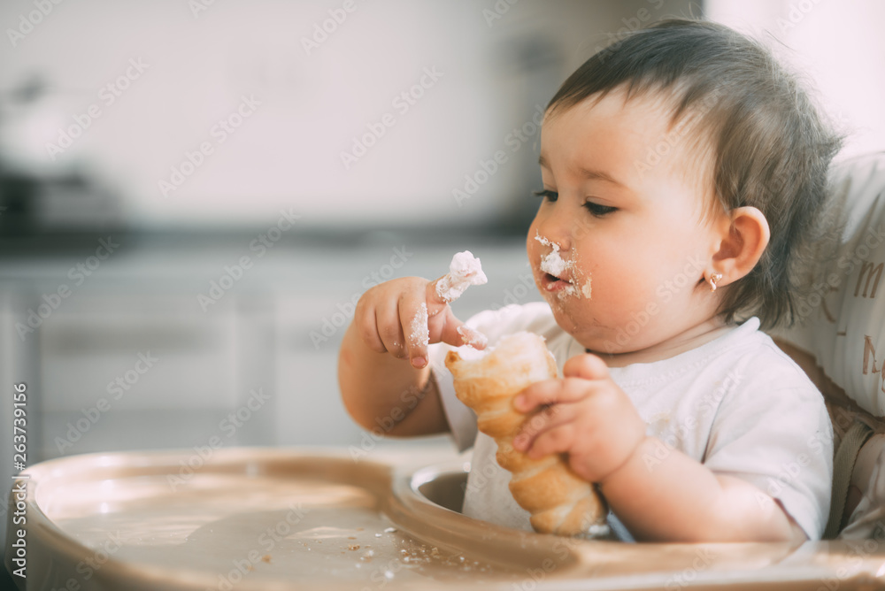 baby in the kitchen eagerly eating the delicious cream horns, filled with a vanilla cream baby in the kitchen eagerly eating the delicious cream horns, filled with a vanilla cream