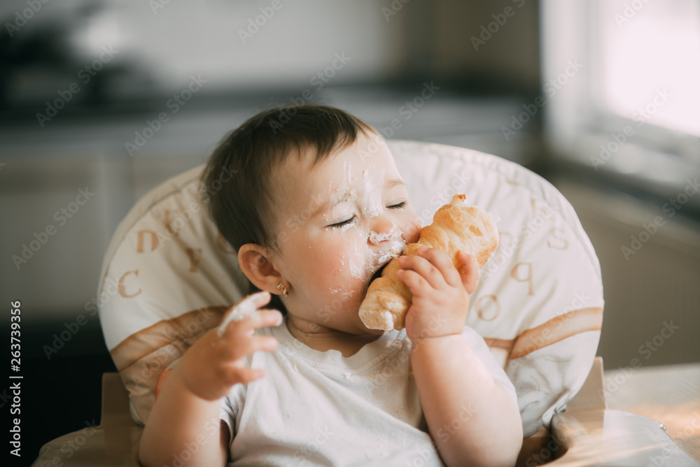 baby in the kitchen eagerly eating the delicious cream horns, filled with a vanilla cream baby in the kitchen eagerly eating the delicious cream horns, filled with a vanilla cream