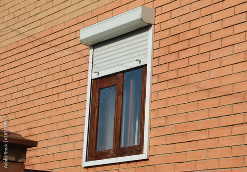Rolling shutters house windows protection. Brick house with metal roller shutters on the windows
