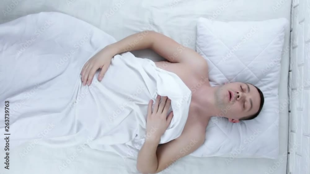 Portrait of young attractive scared man in fear and panic suffering horror nightmare waking up suddenly at night lying on bed Portrait of young attractive scared man in fear and panic suffering horror nightmare waking up suddenly at night lying on bed