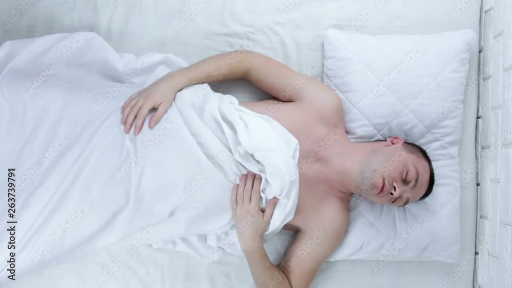 Portrait of young attractive scared man in fear and panic suffering horror nightmare waking up suddenly at night lying on bed Portrait of young attractive scared man in fear and panic suffering horror nightmare waking up suddenly at night lying on bed