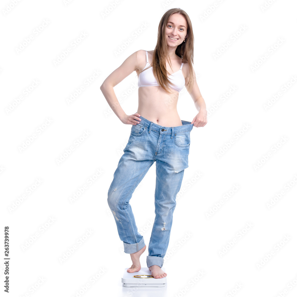 Beautiful woman in big jeans on weighing-machine, weight loss slimming on a white background. Isolation Beautiful woman in big jeans on weighing-machine, weight loss slimming on a white background. Isolation