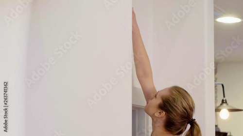 A lady routinely checks a smoke alarm located high up on the wall, 60 fps. photo