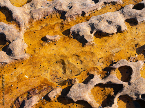 Orange and red rock formations on a beach in Royal National Park in Sydney