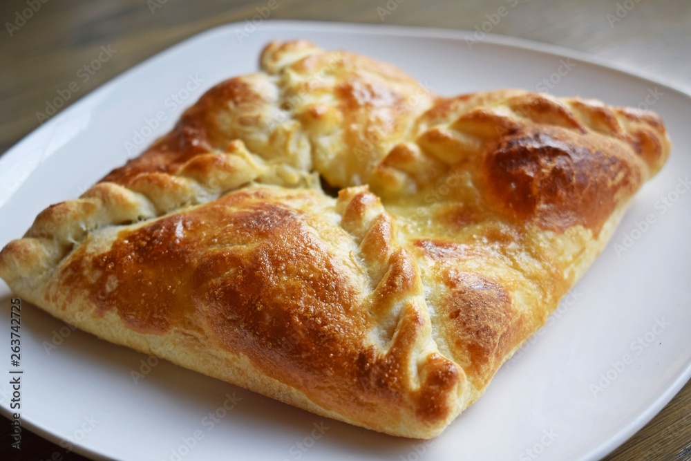 Khachapuri with vegetables and cheese on a white plate.