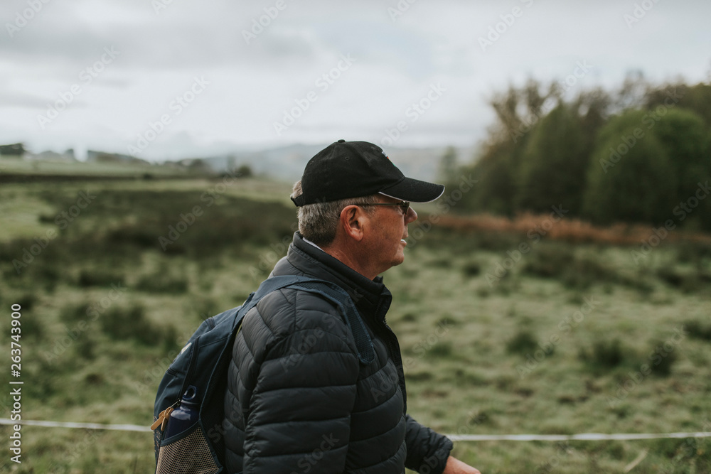 Senior man in cap hiking, viewed from the side.