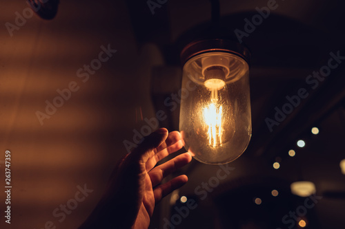 Hand reaching for a vintage light bulb.
