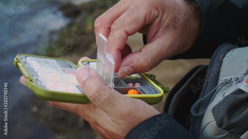 Skilled fly fisherman selects fly from colorful fly box photo