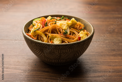 Egg Schezwan/hakka noodles, popular indochinese food served in a bowl with chopsticks. selective focus