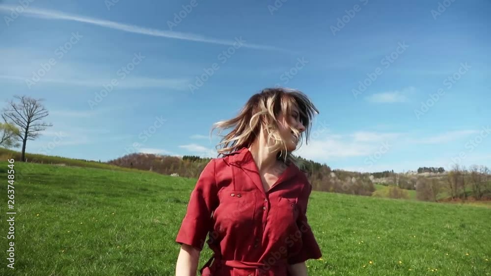 Beautiful girl in red dress and hat have a carefree time on meadow in mountains with forest on background. Spring season Beautiful girl in red dress and hat have a carefree time on meadow in mountains with forest on background. Spring season