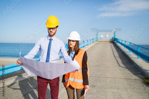 Foto Ingegnere uomo e donna stanno guardando il progetto sul foglio a2 di carta prima di valutare i lavori per la costruzione del ponte sl mare