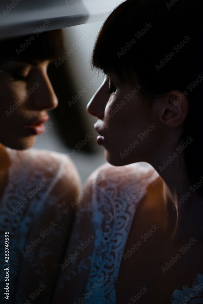 Young attractive woman in white lace nightgown looking at the mirror at home. Lingerie and nightwear. Mirror reflection Young attractive woman in white lace nightgown looking at the mirror at home. Lingerie and nightwear. Mirror reflection