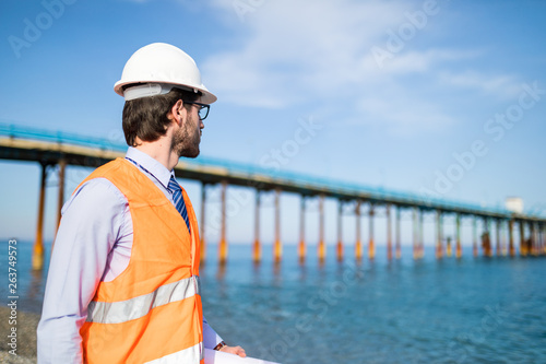 Ingegnere navale guarda la costruzione di un ponte sul mare dalla costa. photo