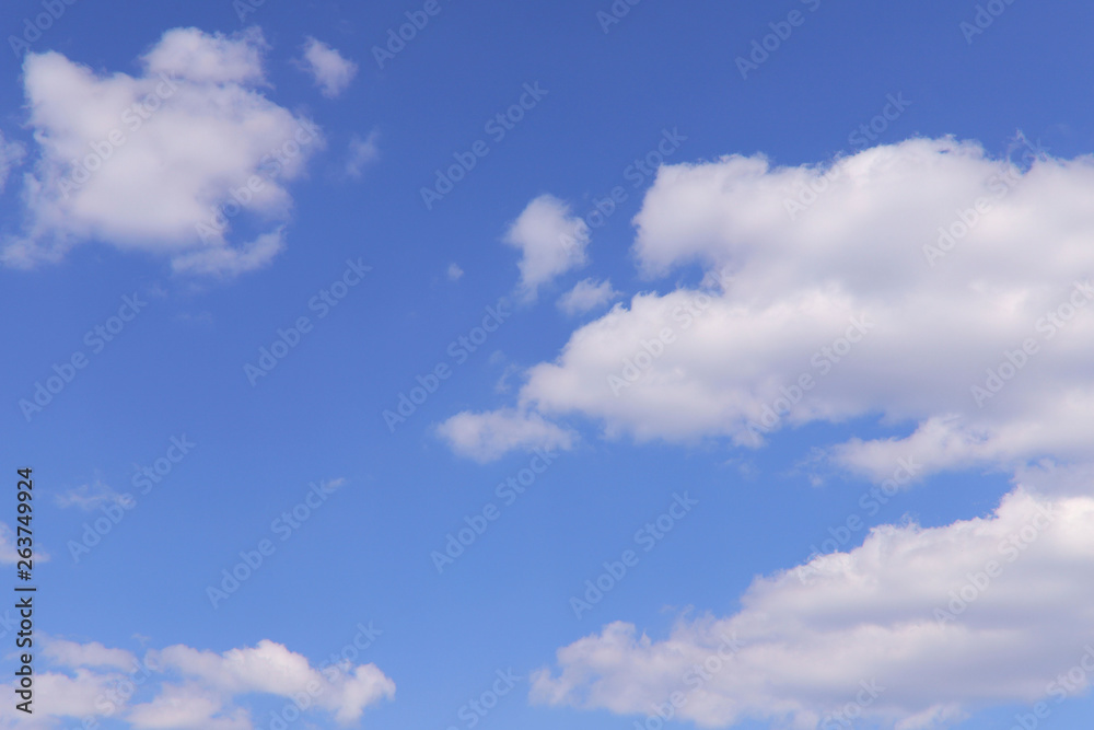 Fototapeta premium Tło błękitnego nieba z białymi chmurami w słoneczny dzień. Koncepcja natury. Poziomo, dużo miejsca na tekst.