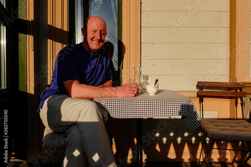 Sandviken, Sweden A man has dinner by himself on a sunny porch. photo