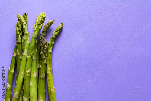 Buncj of green asparagus on purple background with copy space