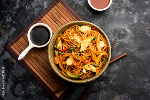 Egg Schezwan/hakka noodles, popular indochinese food served in a bowl with chopsticks. selective focus photo