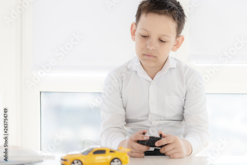 teen boy plays with the car on the Radio controlled models sitting at a Desk on white background