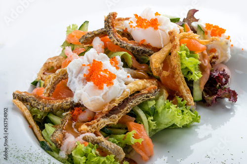 Salad with salmon belly, shrimp and poached egg. On white background