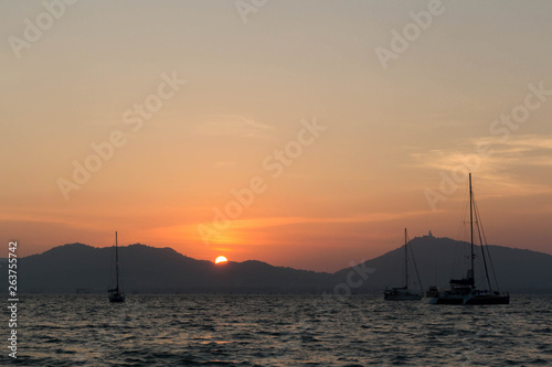 Sunset and dawn at sea against a backdrop of mountains and boats © 4iffa