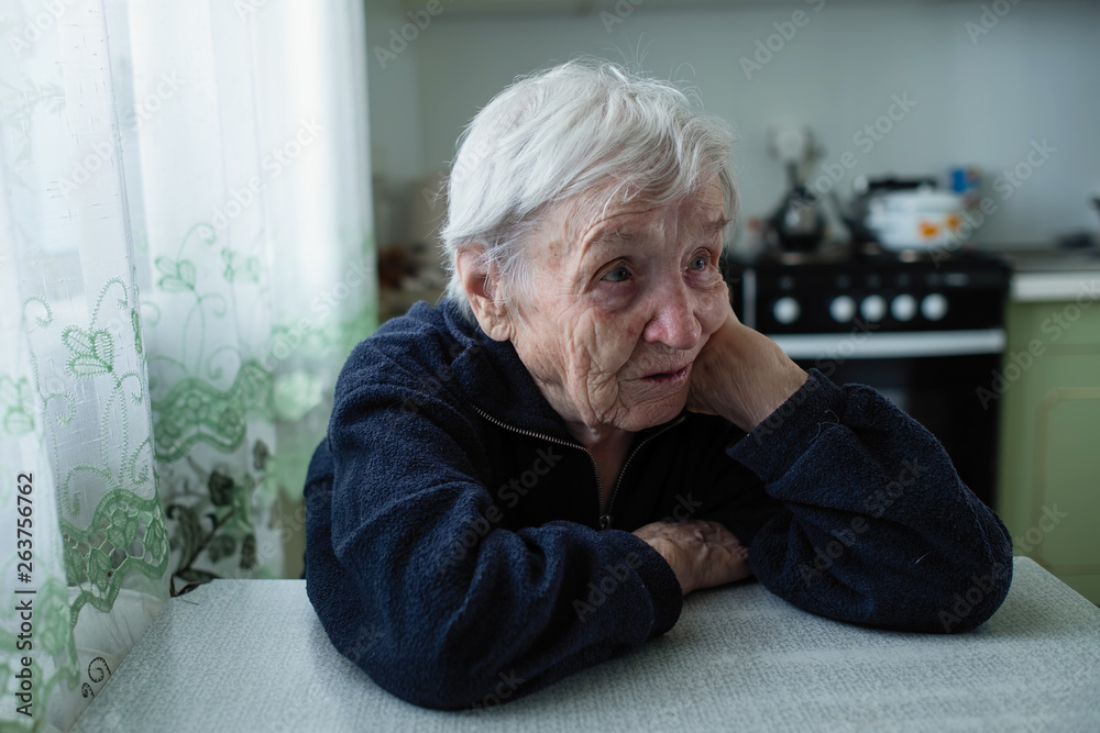 Sad elderly woman portrait near window in the house. Sad elderly woman portrait near window in the house.