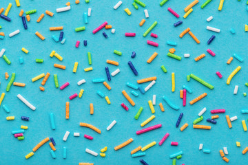 colorful sprinkles over turquoise background, festive decoration for banner, poster, flyer, card, postcard, cover, brochure