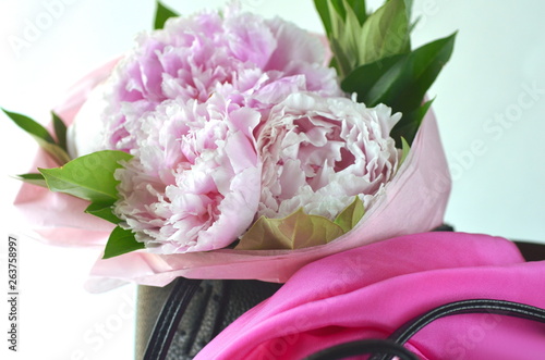 Light pink peony bouquet wrapped in tissue paper in tote bag with copy space photo