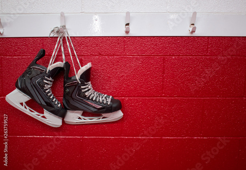 Photography Hockey skates hanging in locker room over red background with copy space