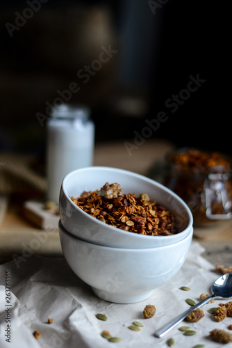 tasty homemade oats granola with nuts and berries in white ceramic bowl served with coconut milk on the wood table for breakfast early in the morning